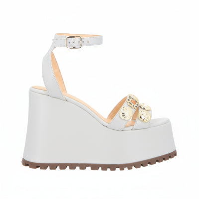 White wedge sandal with gold embellishments on a white background