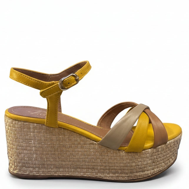 Yellow high-heeled shoes with woven design on a black surface, with boxes and people in the background.