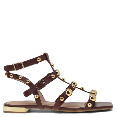 Brown sandal with gold straps and embellishments on a white background