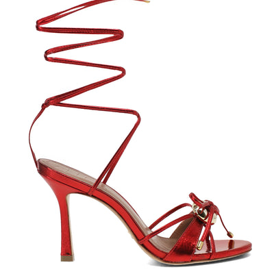 Red high-heeled sandal with a unique strap design on a white background